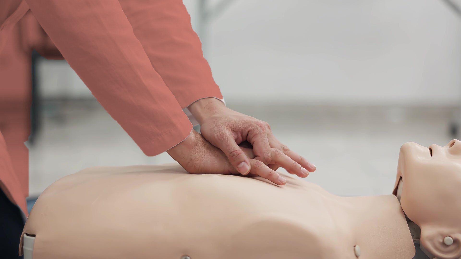 Hands giving chest compressions to a CPR training manikin